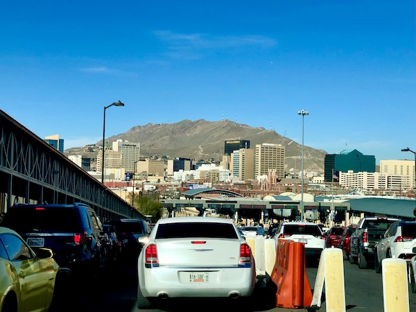 Cars driving from the Mexican border crossing and mountain with buildings on it from Our Trip to Mexico and Lunch