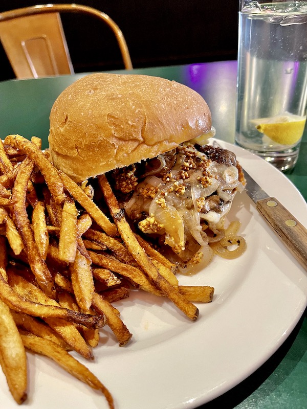 A white plate topped with golden brown fries and a burger topped with onions from Our Trip to Mexico and Lunch
