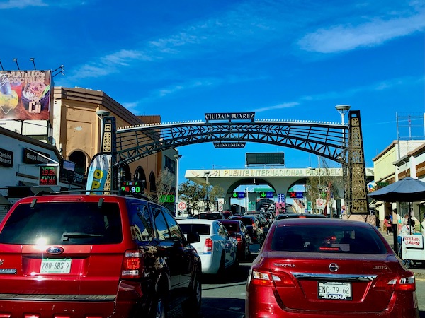 Rows of cars heading under a wrought iron arch to the border crossing from Our Trip to Mexico and Lunch