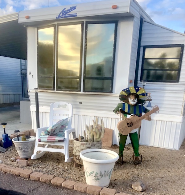 A rocking chairs and a statue of a man playing guitar while wearing a sombrero in front of a mobile home in Tucson AZ