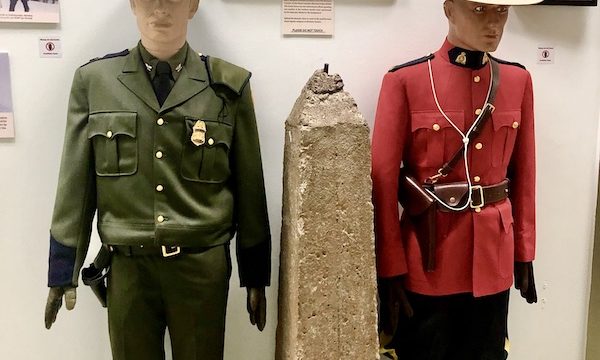 Two mannequins, one on left in olive green uniform with riding pants and the one on the right in red. On display at the US Border Patrol Museum El Paso