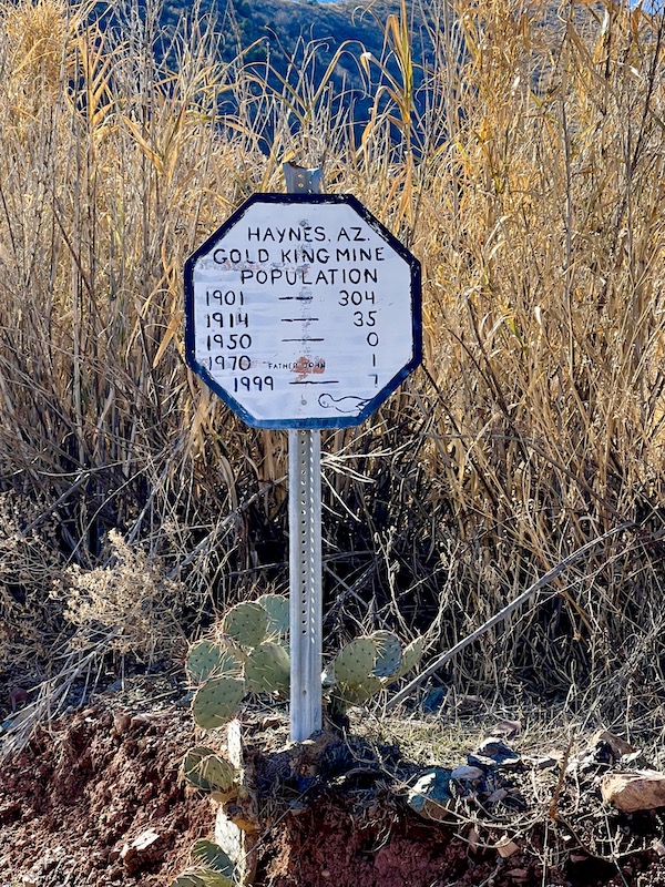 A white octagonal sign listing the population of Friendly Ghost Town Haynes AZ over the years.