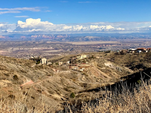 Spectacular vista from a mountaintop looking out over homes and mountains in the distance.