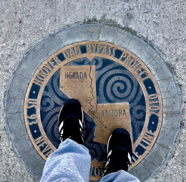A man's legs and feet standing with one foot in Nevada and one in Arizona
