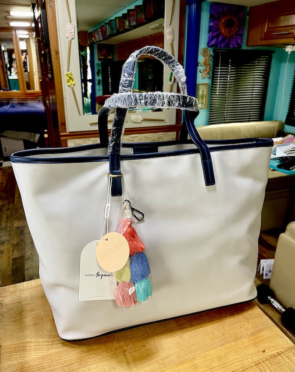 A light gray tote with black trim and plastic still on the handles.