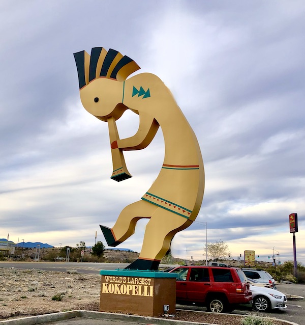 A enormous statue of kokopelli in yellow and brown.