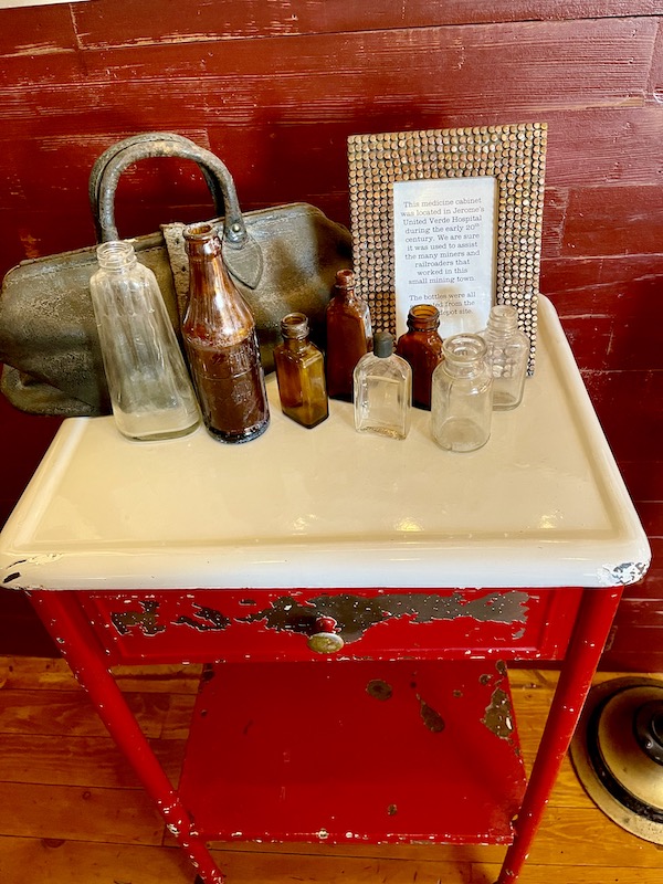 A white topped red cabinet with antique bottles displayed