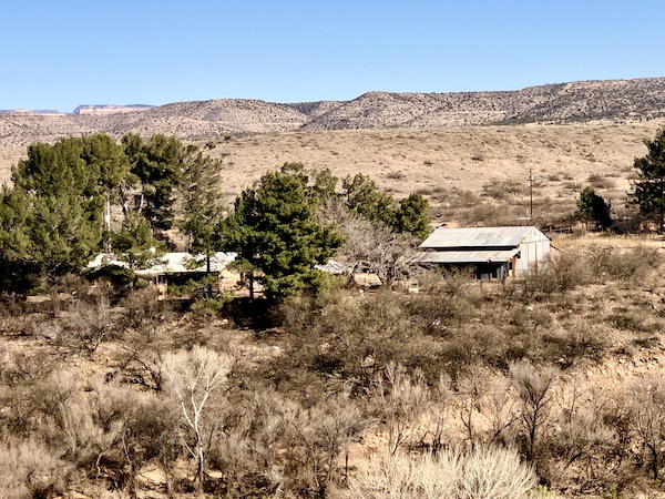 Rough terrain with white buildings and trees along our Verde Canyon Railroad Wilderness Route