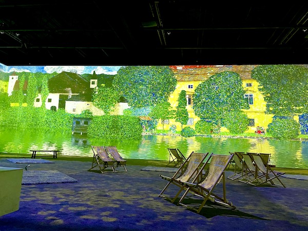 Digital projection of a painting of yellow houses and trees at the Gustav Klimt: The Immersive Experience