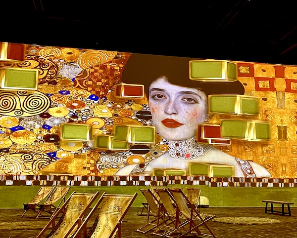 Portrait of a woman with black hair and a jeweled collar necklace with multicolored blocks.