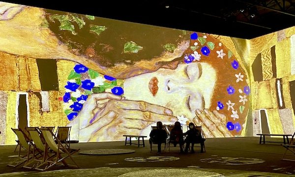 A portrait of a man kissing a woman with colorful overlays at the Gustav Klimt: The Immersive Experience