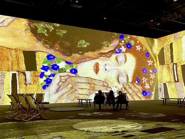A portrait of a man kissing a woman with colorful overlays at the Gustav Klimt: The Immersive Experience