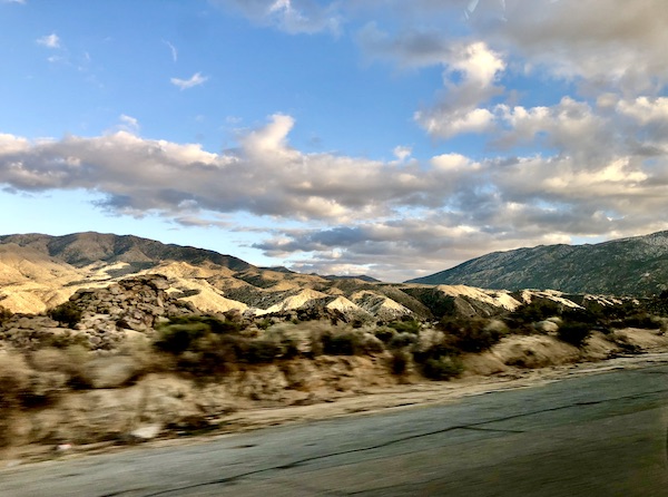 Rocks, desert plants, mountain and blue sky with white clouds on our way home from La Quinta Art Celebration California
