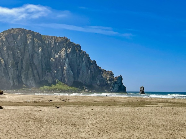Sand, ocean and blue sky with partial close up of Morro Bay California's namesake rock.