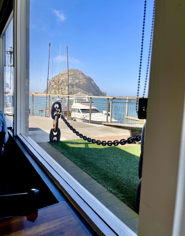 Looking through a restaurant window in Morro Bay California, at bay and rock.