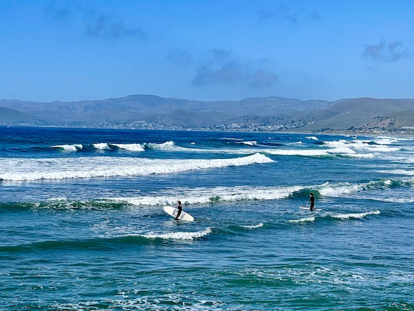 The Pacific Ocean, mountains, blue sky and surfers at We were staying at beautiful Vines RV Resort in Paso Robles, California and decided to go to Morro Bay for the day.