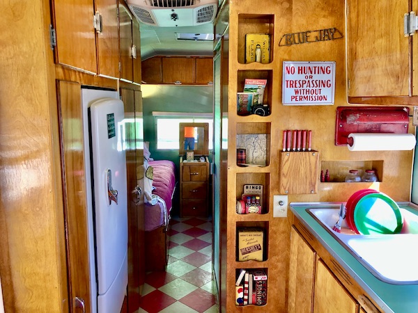 Wood interior with lots of cubby holes for storage. View looks into the bedroom of this vintage trailer at the Palm Springs CA Vintage Trailer Show