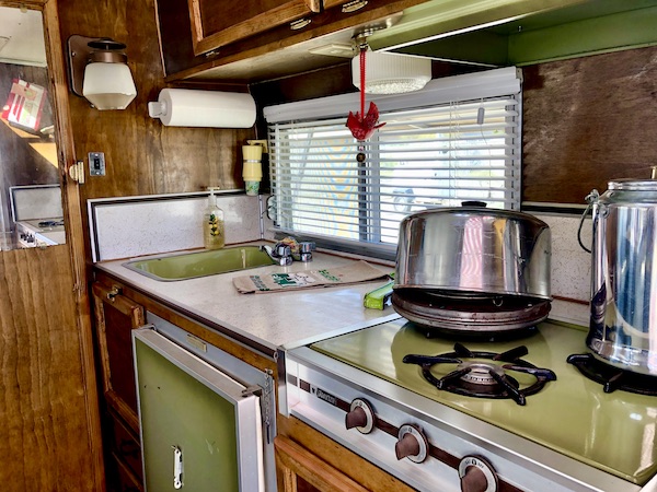 Vintage kitchen in a camper with light green counter and stove at the Palm Springs CA Vintage Trailer Show