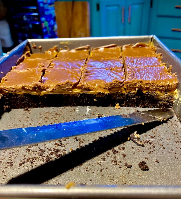 A baking pan that's half filled with cut brownies showing off the layers from the Peanut Butter Brownies Recipe