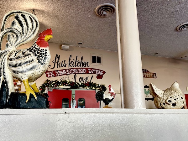 A wall with a pillar and a display of wood and ceramic chickens and roosters at The Egg House Simi Valley CA