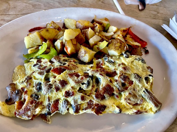 A large white plate topped with a mushroom, sausage and cheese omelet and hash brown potatoes at The Egg House Simi Valley CA