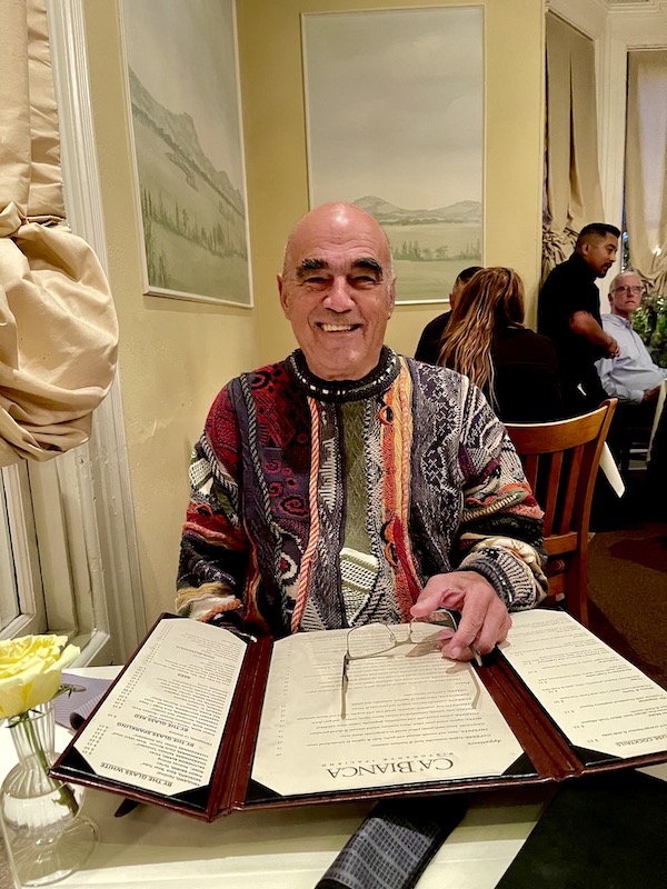 A man in a multicolored sweater seated at a dining table at Ca' Bianca Ristorante Italiano