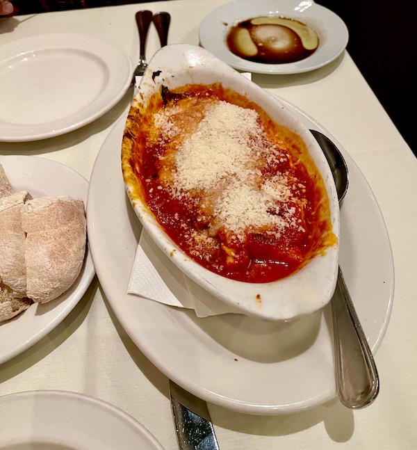 An oval white baking dish filled with tomato sauce, cheese and polenta at Ca' Bianca Ristorante Italiano