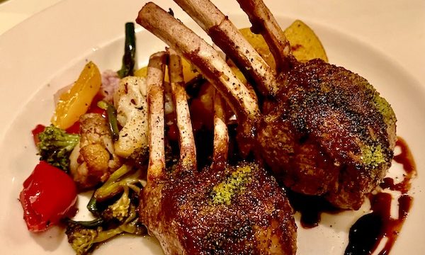 A white plate topped with lamb chops and assorted vegetables at Ca' Bianca Ristorante Italiano