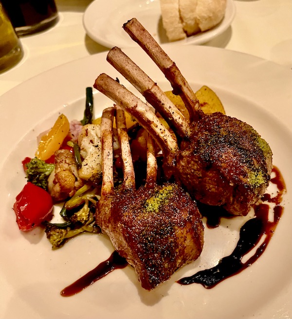 A white plate topped with lamb chops and assorted vegetables at Ca' Bianca Ristorante Italiano