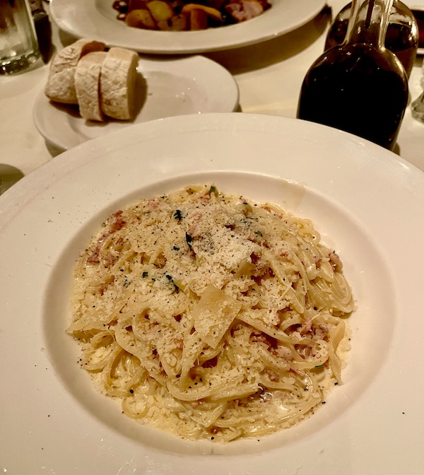 A round white plate topped with spaghettini and white sauce at Ca' Bianca Ristorante Italiano