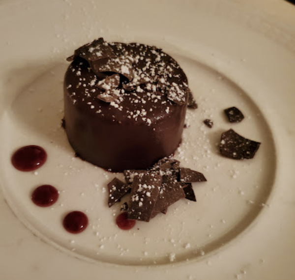 A white plate with dots of sauce and an individual chocolate mousse cake at Ca' Bianca Ristorante Italiano