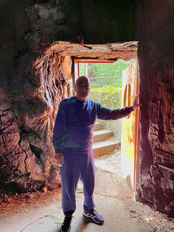 A man holding a door open inside a tree.