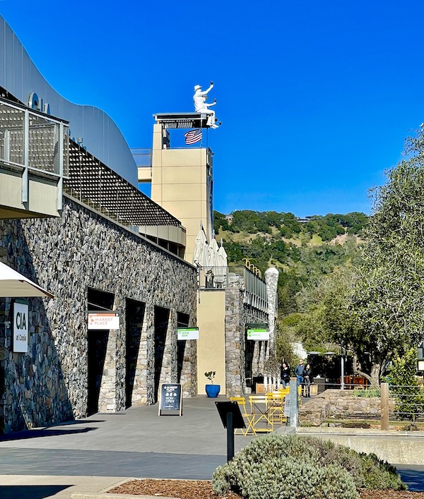 A stone and stucco building with trees and mountains seen while having Fun in Downtown Napa CA