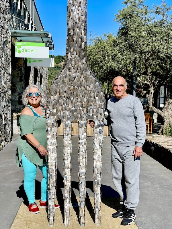 A man and a woman standing on either side of a huge fork sculpture while having Fun in Downtown Napa CA