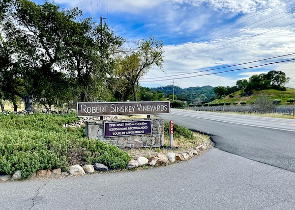 Trees, plants, mountains and a brown sign at the entry to a winery on our Napa Valley Winery Tour