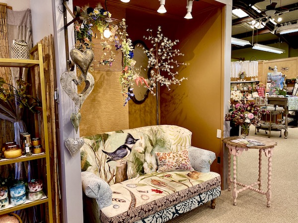 A jewelry boutique with chandelier and yellow floral print loveseat at Holly Yashi Store and Studio