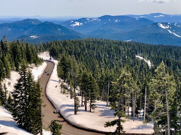 A road cutting through the snow and lots of trees and mountains on our way up Mt. Hood Oregon