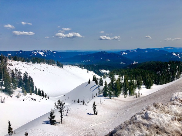 Snow covered mountain with trees and more mountains in the distance on our way up Mt. Hood Oregon