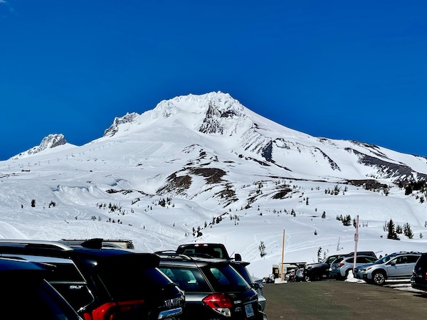 A parking lot with cars and awesome view of a snow cover mountain which is Mt. Hood Oregon