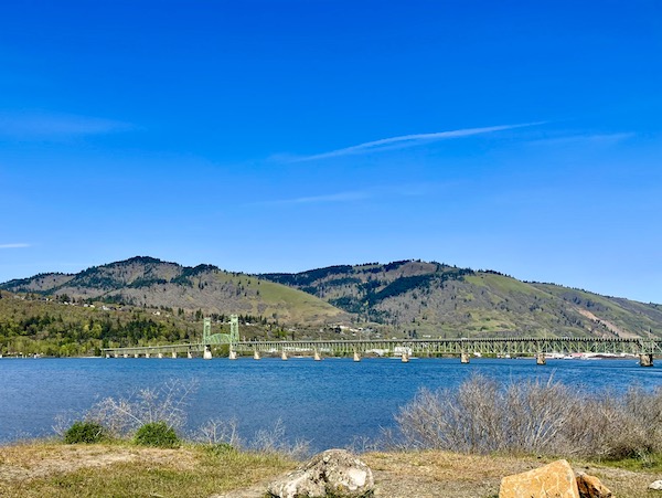 A long green bridge spans a river with mountains on our way home from Mt. Hood Oregon