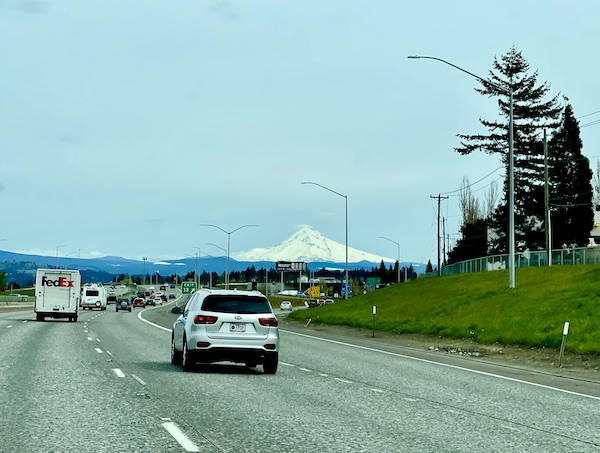 Cars on a highway and a snow covered mountain in the distance on our way to Multnomah Falls Oregon