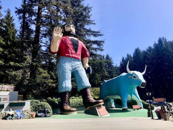 Huge sculptures of a lumberjack and a blue ox in front of trees at the entrance to Trees of Mystery Klamath CA