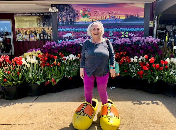 A woman standing a a pair of huge yellow wooden shoes