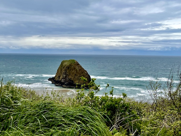 Ocean, grass and a huge rock in Cannon Beach Oregon