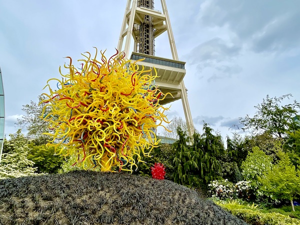 Yellow orb of glass pieces with Space Needle in background at Chihuly Gardens Seattle WA
