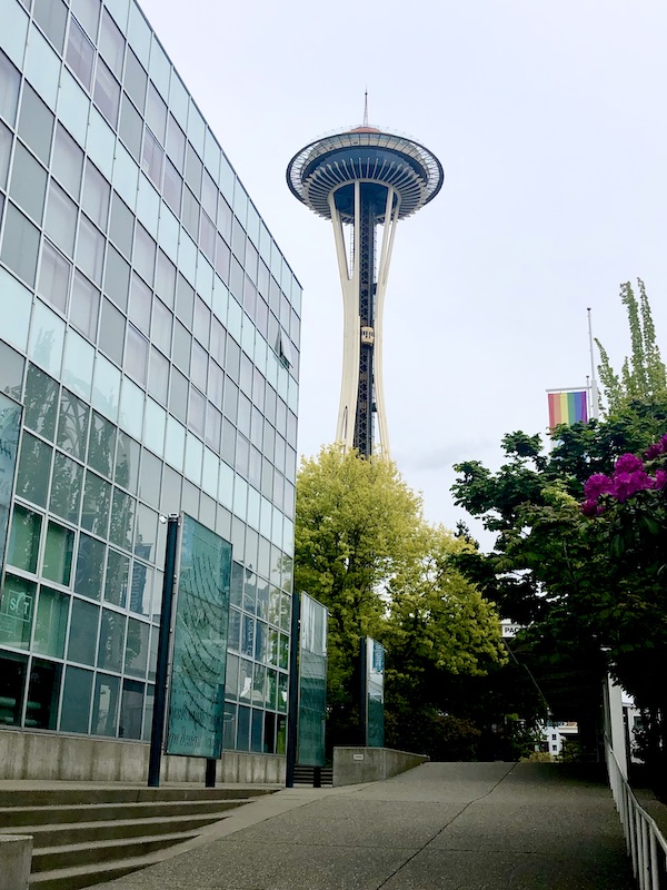 Glass building, trees and the Space Needle near Chihuly Gardens Seattle WA