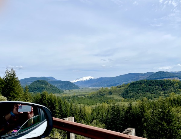 Glimpse of a snow capped mountain from a car with side view mirror visible on our way to Mount St. Helens Washington