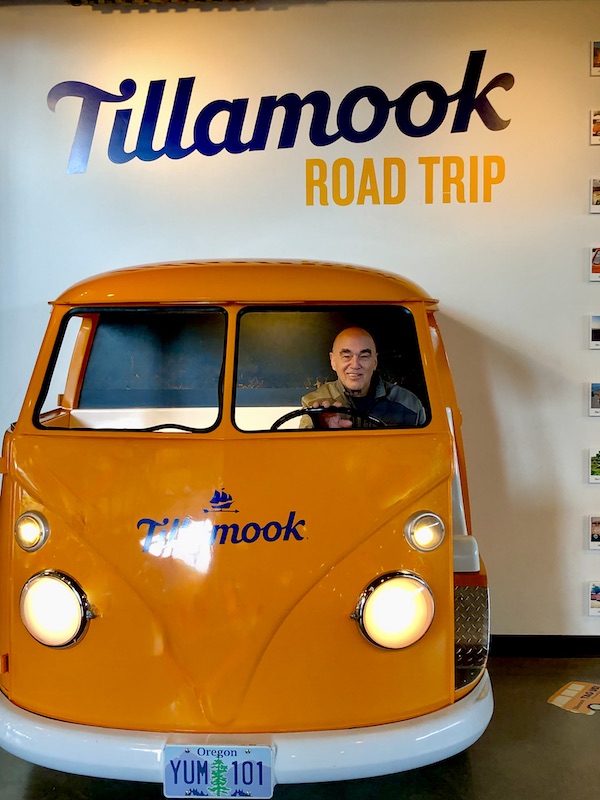 A man seen through the windshield of a yellow VW van at the Tillamook Cheese Factory Tour