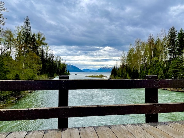 Bridge over lake with views of mountains and trees in Glacier National Park Montana