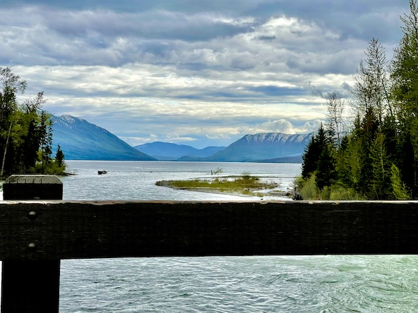 Lake view from a bridge shows mountains and clouds in Glacier National Park Montana